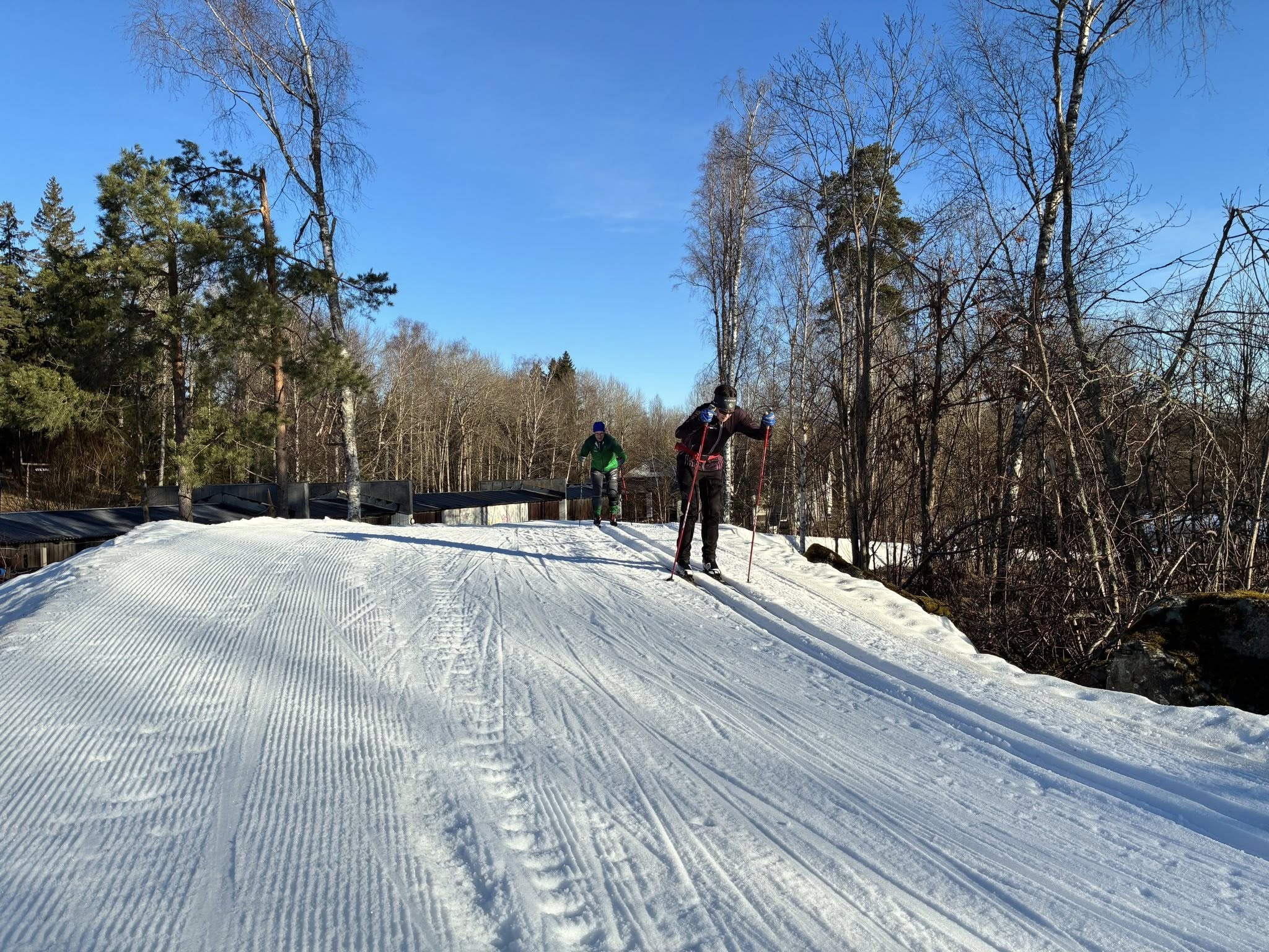 Två skidåkare på det preparerade konstsnöspåret i Ursviks motionsområde, Sundbyberg